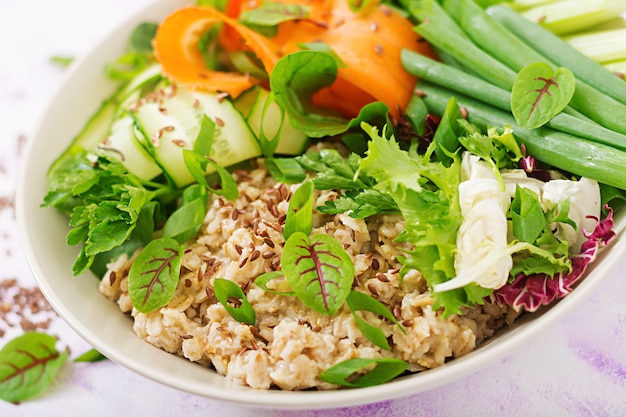 Diet menu. Healthy lifestyle. Oat porridge and fresh vegetables - celery, spinach, cucumber,  carrot and onion  on plate.