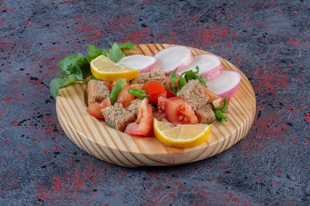 Dietary salad mix and sliced turnips served on a wooden platter on dark colored background. High quality photo