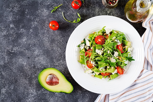 Dietary salad with tomatoes, blue cheese, avocado, arugula and pine nuts.