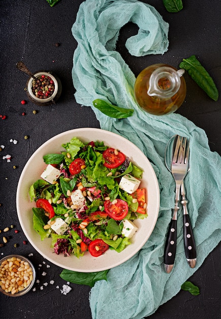 Free photo dietary salad with tomatoes, feta, lettuce, spinach and pine nuts. top view. flat lay.