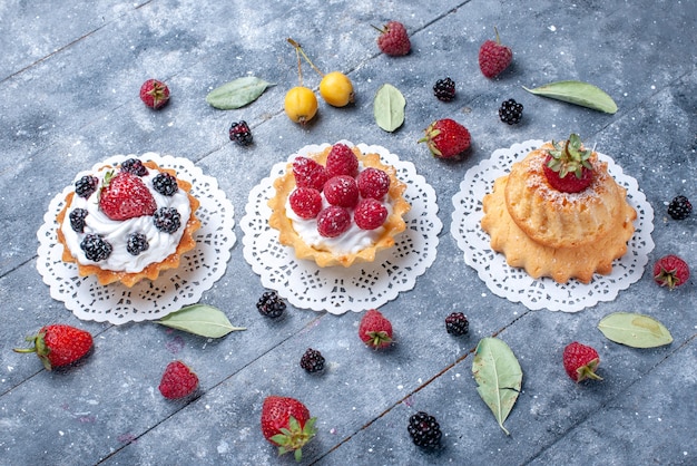 Free photo different creamy cakes with berries along with fresh fruits on bright desk, berry fresh fruit