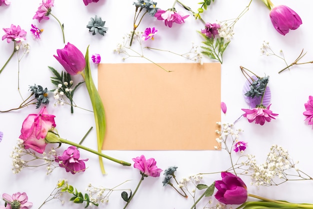 Different flowers with blank paper on table