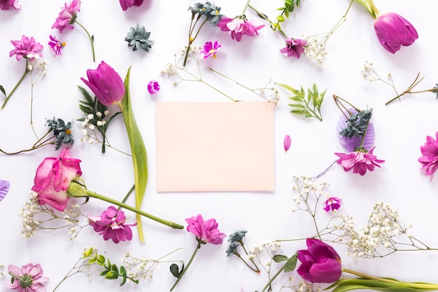 Different flowers with paper on white table