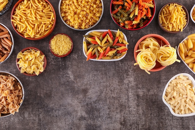 Free photo different kids of pasta in plates top view with copy space on gray surface