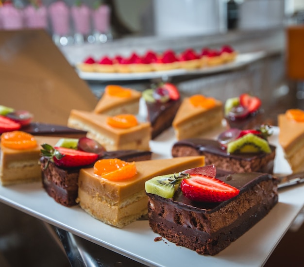 Free photo different kinds of cream, caramel and chocolate cakes with fruits on the top