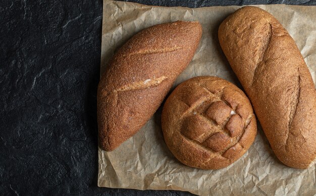 Different loaves bread on black background.