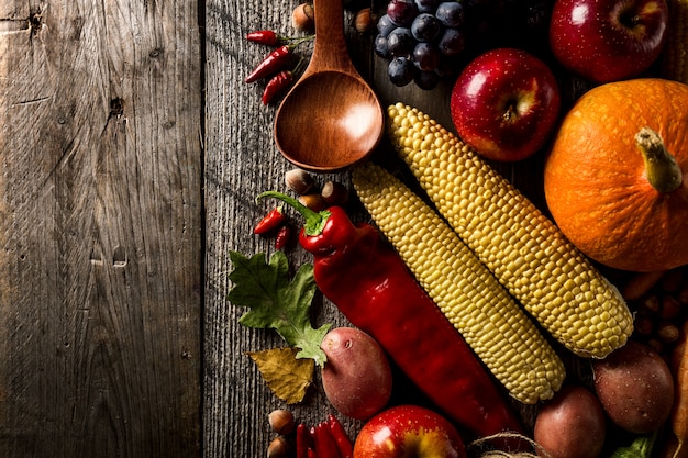 Different seasonal autumn vegetables and fruits on wooden background