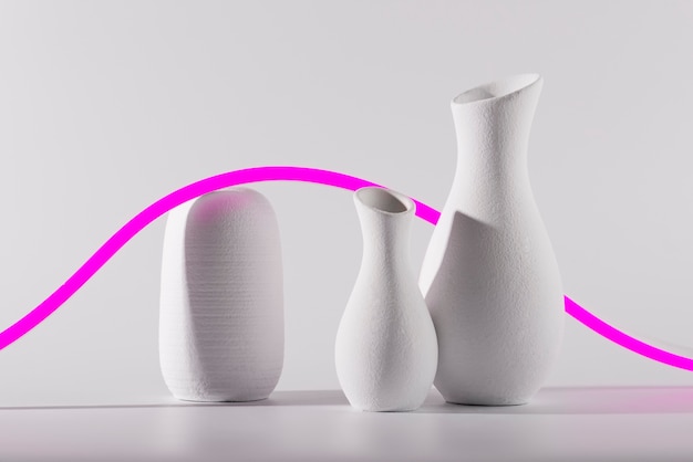 Free photo different shaped vases and pink line