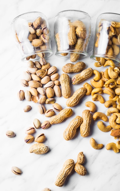 Free photo different spilled out dried fruits on marble background