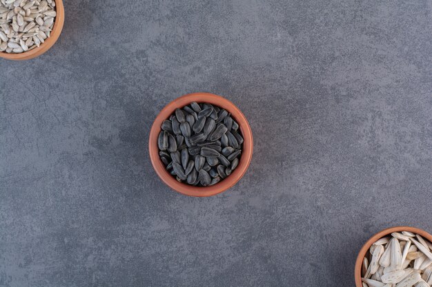 Different sunflower seeds in bowls , on the blue surface