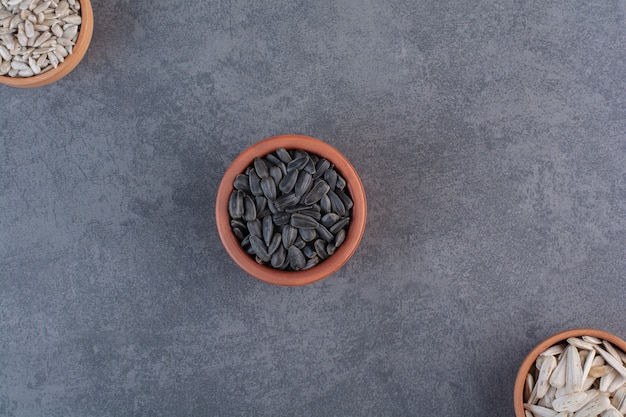 Different sunflower seeds in bowls , on the blue surface