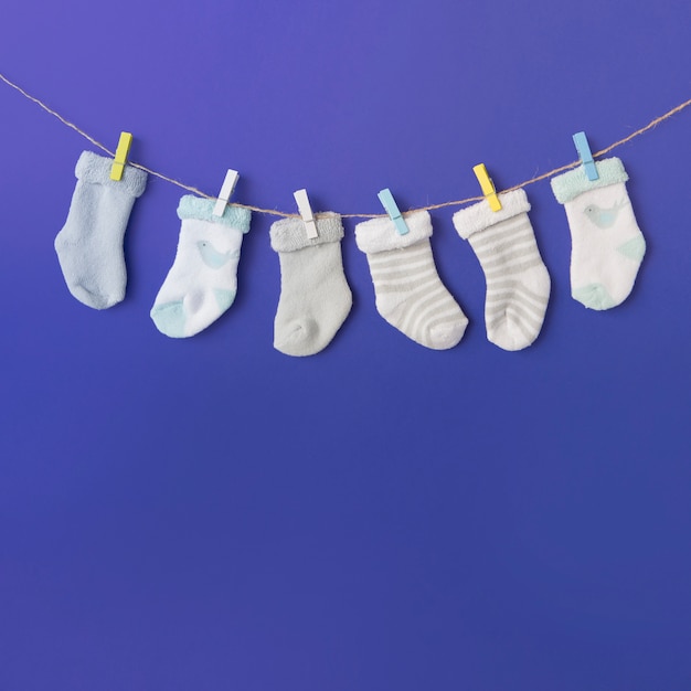 Free Photo different type of baby's sock hang on clothesline against blue backdrop