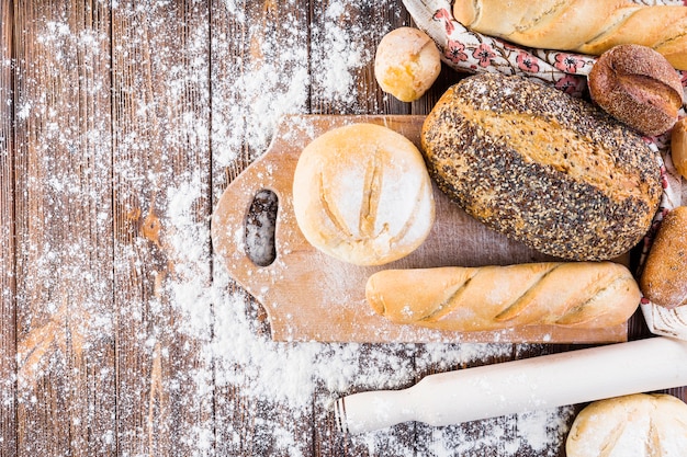 Different type of baked breads with flour on the wooden table