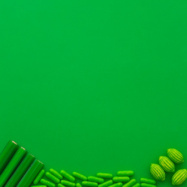 Free photo different type of candies at the bottom of green background