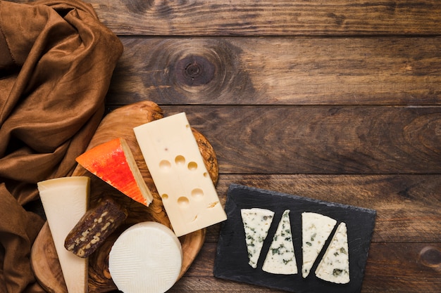 Different types of cheeses and brown silk textile on table