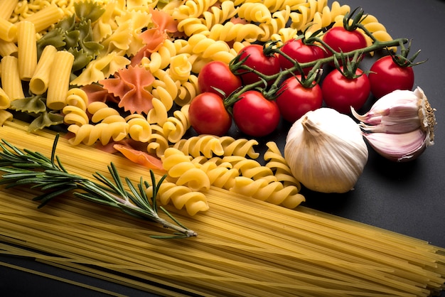 Free photo different uncooked pasta with fresh ingredients