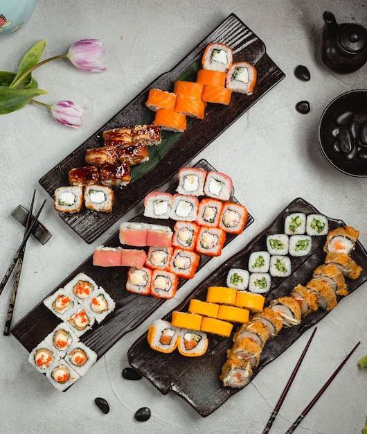 Different variety rolls with chopsticks on a black plate.