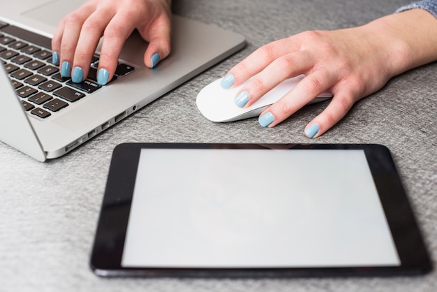 Free photo digital tablet near the businesswoman's hand using laptop and mouse on desk