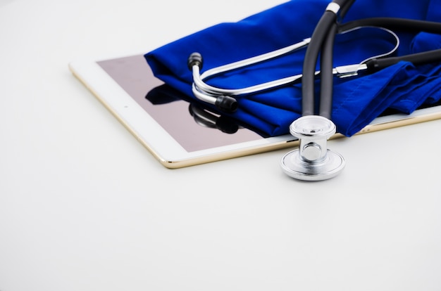 Free Photo digital tablet; stethoscope and medical gown on white backdrop