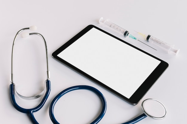 Free Photo digital tablet with blank screen; syringe and stethoscope on white background