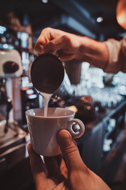 Free photo diligent barista is prepairing fresh latte for customers for coffee break at caffeteria.