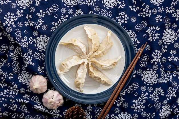 Dim sum in a white plate with garlic on a floral blue background