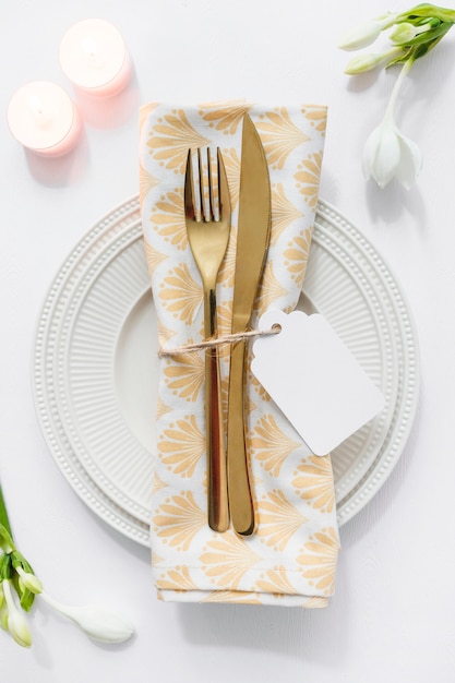 Dining table setting with folded napkin and candles on white background