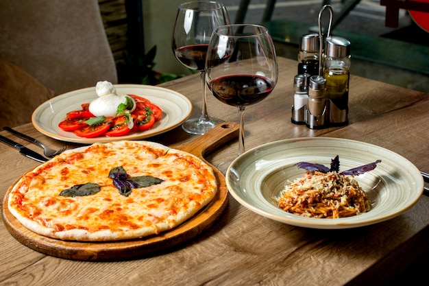 Dinner set with margherita pizza, salad, pasta and wine