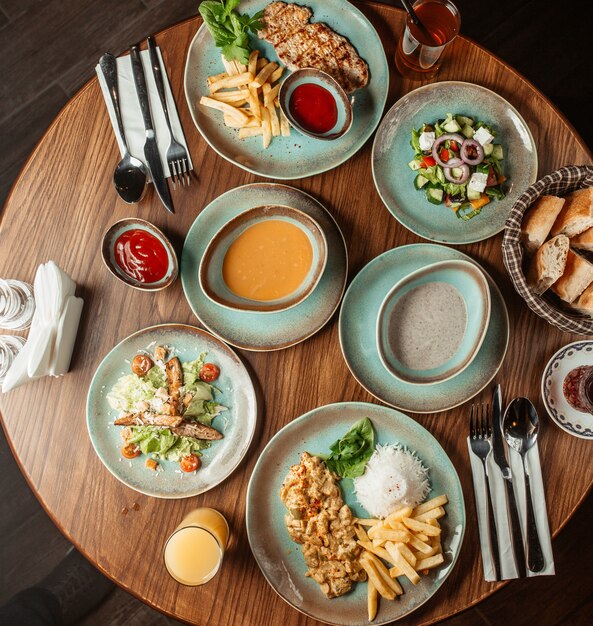 Dinner set with mushroom and lentil soups, salads and chicken with french fries and rice