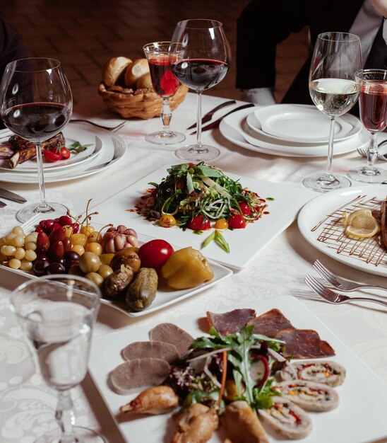 dinner setup with red wine, pickle plate, meat plate, fresh salad