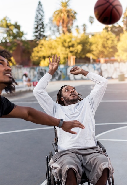 Free photo disabled man in wheelchair playing basketball with people