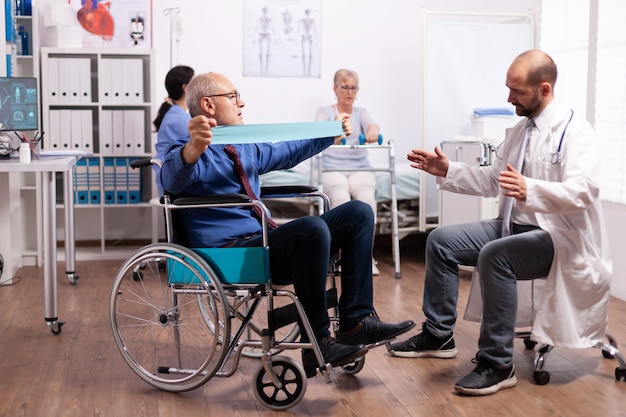 Disabled senior man doing his exercises in hospital with doctor