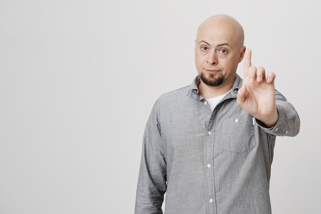 Disappointed bald middle-aged man shaking finger, scolding or prohibit