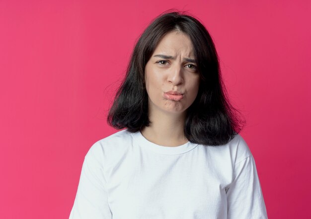 disappointed young pretty caucasian woman looking at camera isolated on crimson