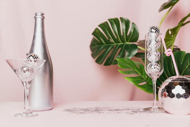 Free photo disco balls in champagne glasses and monstera plant