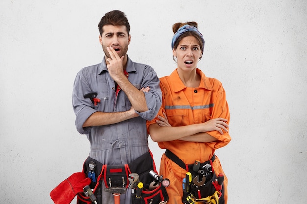 Free Photo discontent handyman and his female partner look at object they should repair, realize all difficulties,