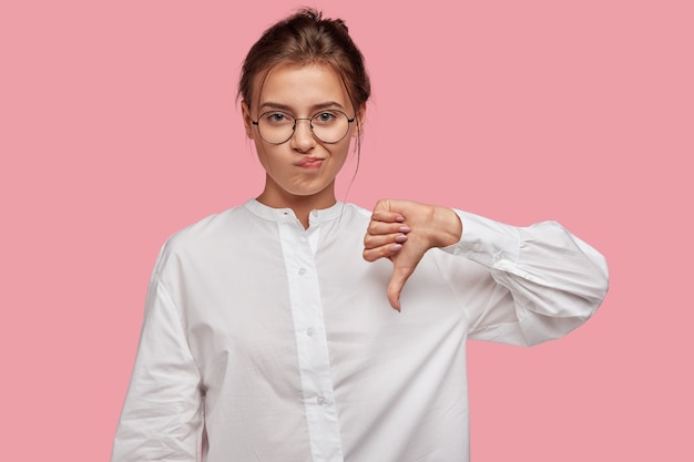 Free photo discontent young woman with glasses posing against the pink wall