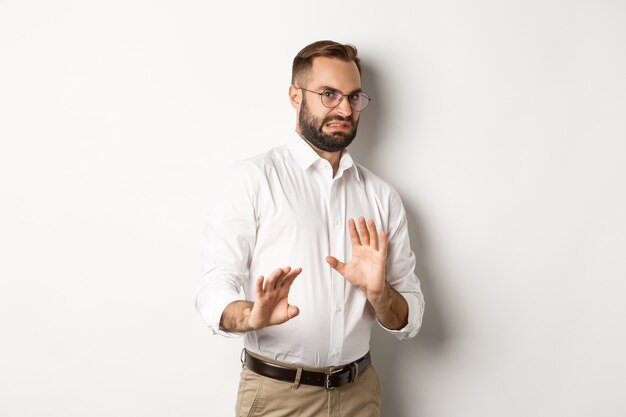 Disgusted businessman rejecting something bad, cringe from aversion, showing stop sign, standing