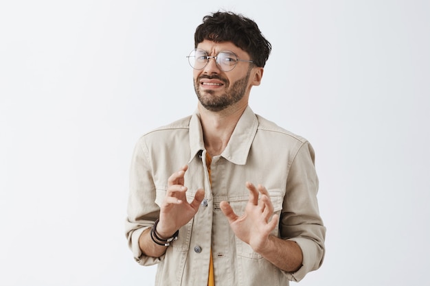 Free photo disgusted stylish bearded guy posing against the white wall