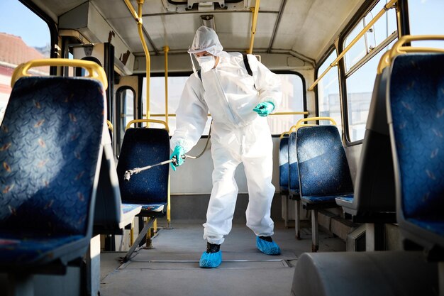 Disinfectant worker spraying inside of a public bus due to coronavirus pandemic