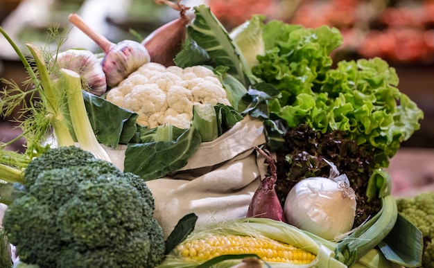 Free photo display of fresh ripe organic broccoli, salad with greens and vegetables in cotton bag at the weekend farmer's market