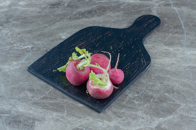 A display of radishes on the cutting board on the marble table. 