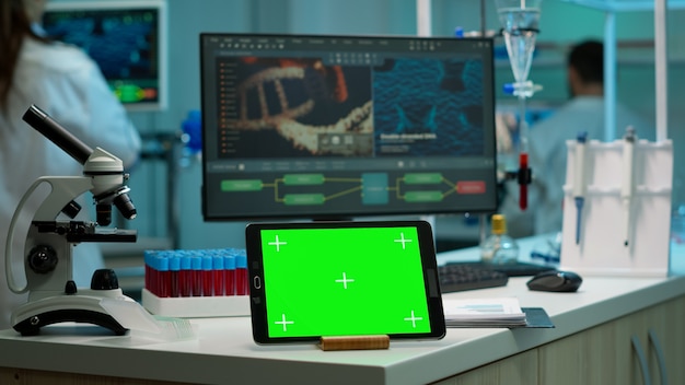 Free Photo display tablet with green screen, mock up on template placed on desk in scientific laboratory while woman medical research scientist analysing virus evolution at digital monitor conducting experiment