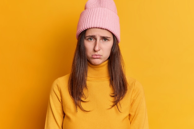 Free photo displeased brunette young woman has offended expression sulky look expresses negative emotions wears hat and casual jumper.