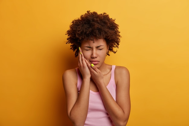 Free Photo displeased dark skinned woman suffers from toothache