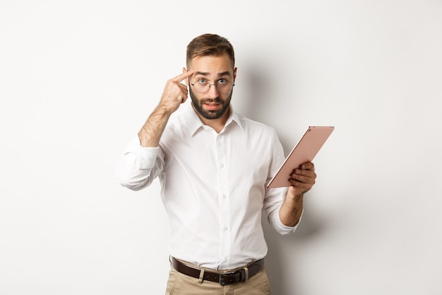 Displeased employer scolding staff while checking report on digital tablet, pointing at head and looking disappointed, standing  