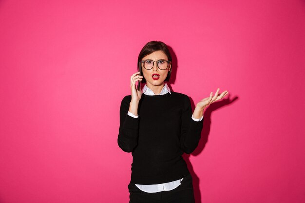 Displeased young lady talking on smartphone isolated