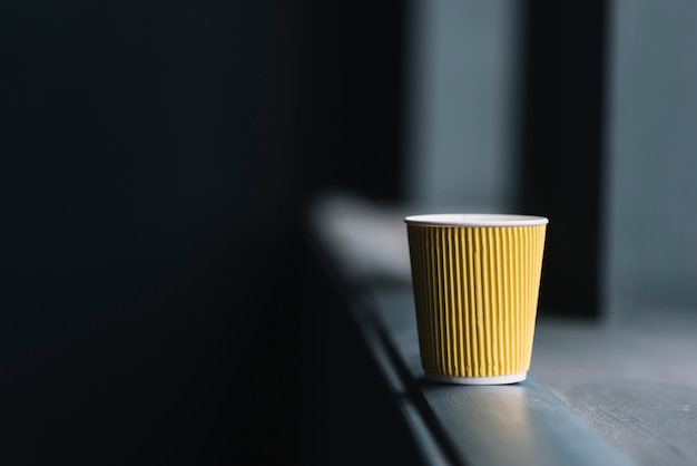 Free photo disposable coffee cup on the edge of window sill