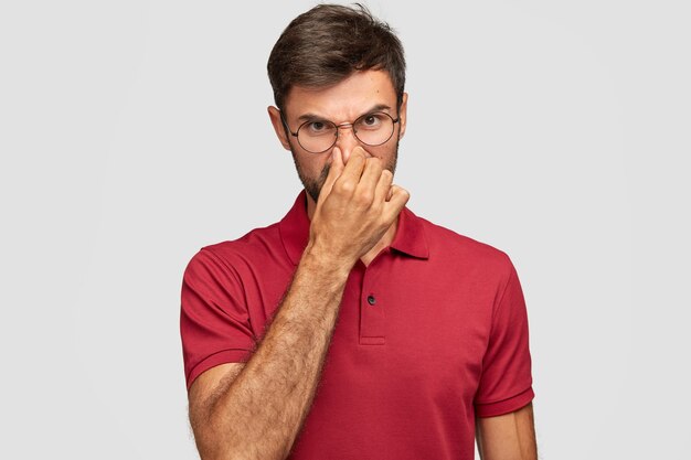 Dissatisfied young emotional man posing against the white wall