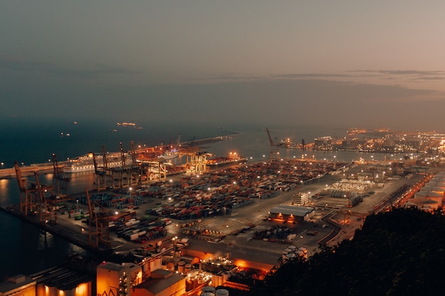 Free Photo distant shot of a port with boats loaded with cargo and shipment during nighttime